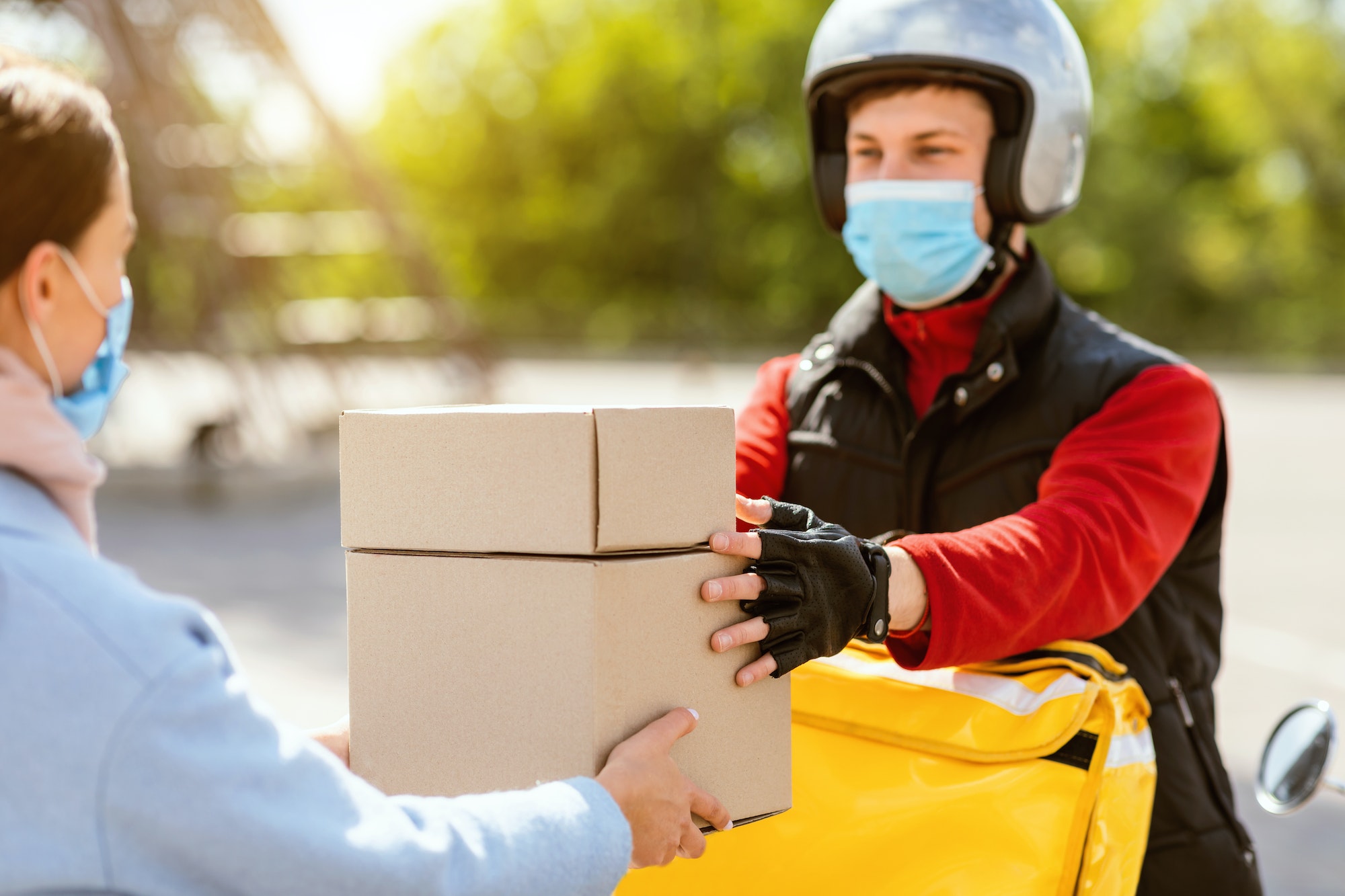 Courier In Medical Mask Giving Lunch Boxes To Girl Outdoor