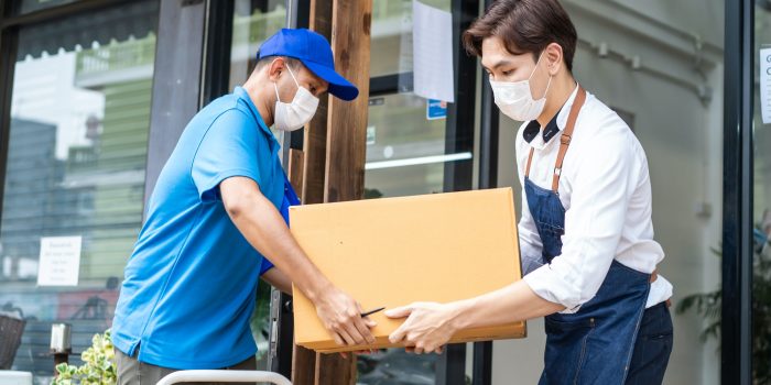 Asian Postman delivery send food ingredients box deliver to restaurant waiter in coffeehouse