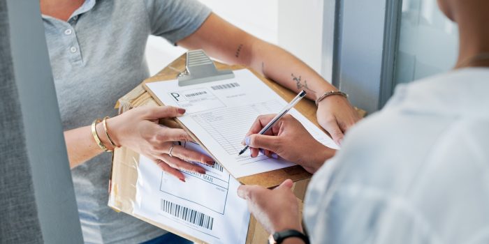 Cropped shot of an unrecognizable woman standing and signing for her package from the courier